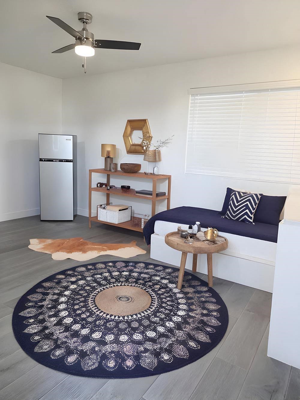 A living room with a couch, a rug, and a ceiling fan.