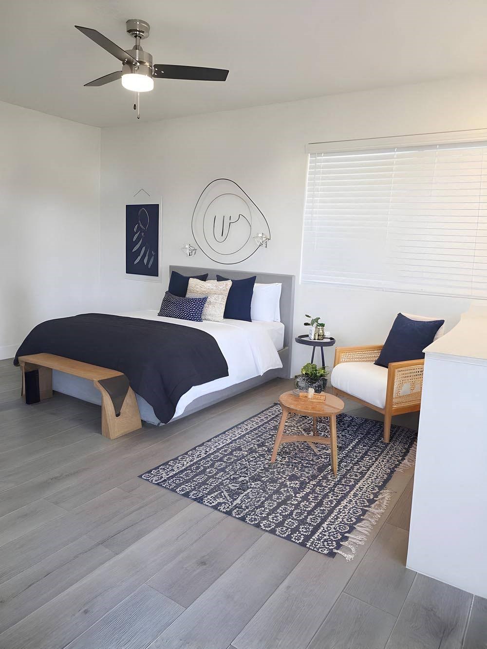 A bedroom with a bed, a bench, and a rug.