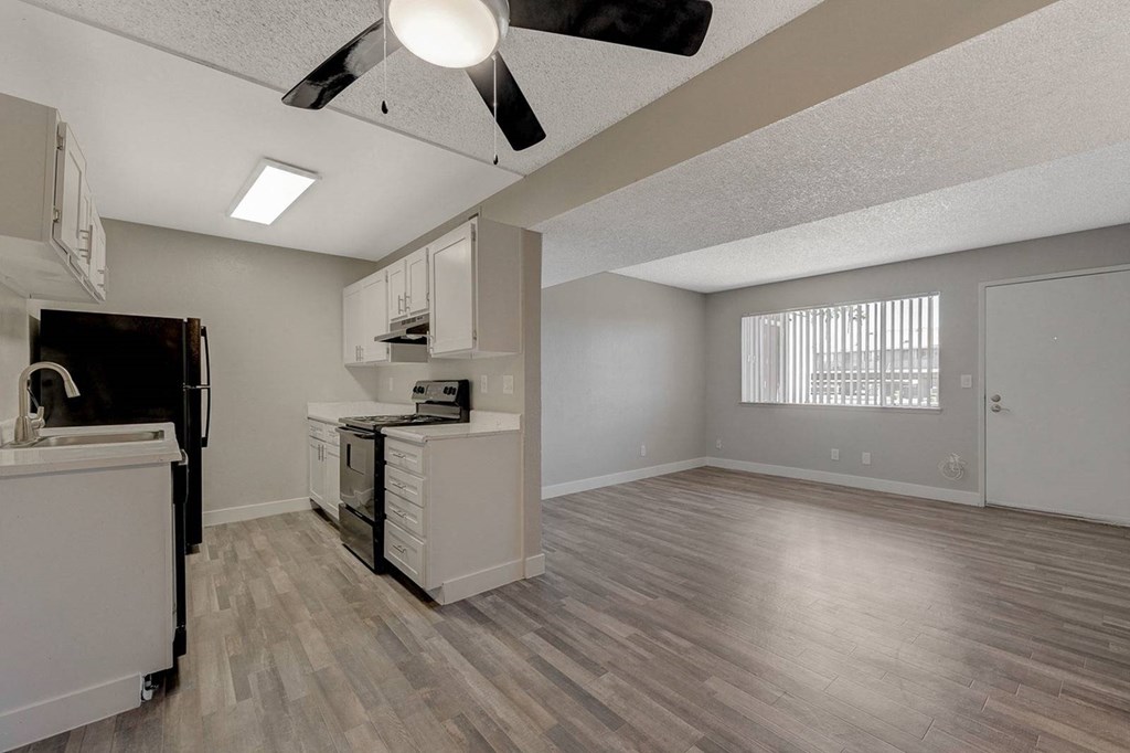 A kitchen with a black refrigerator and white cabinets.