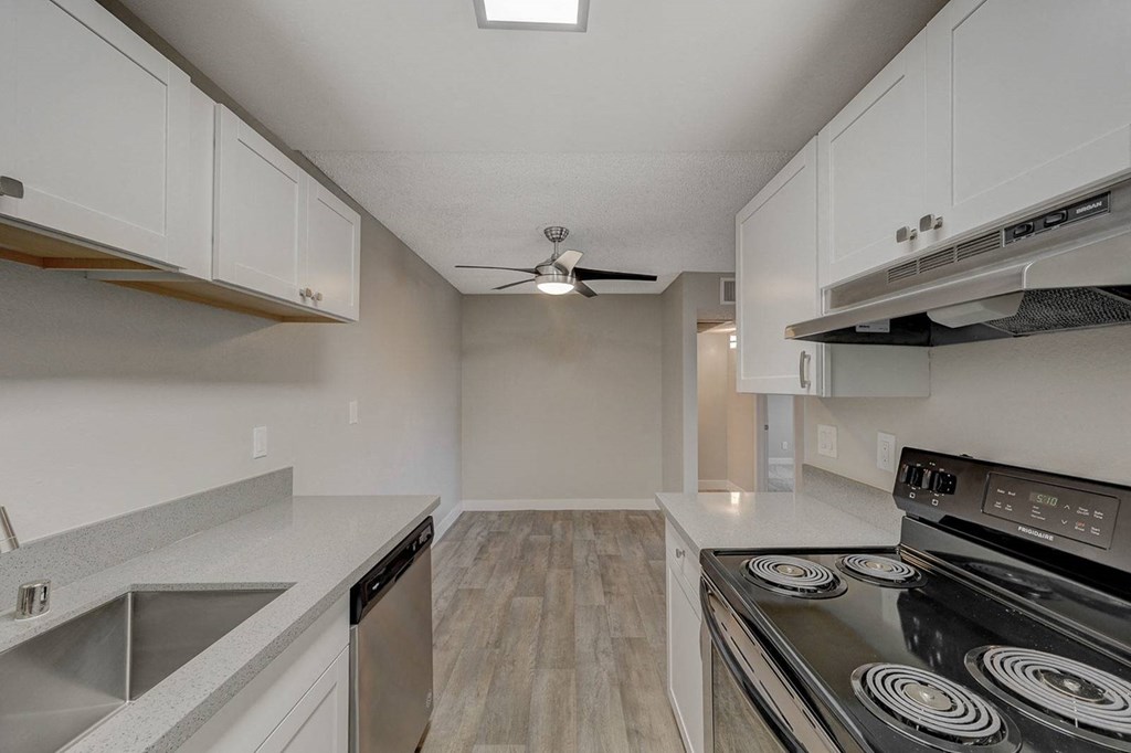 A modern kitchen with a stove, sink, and cabinets.