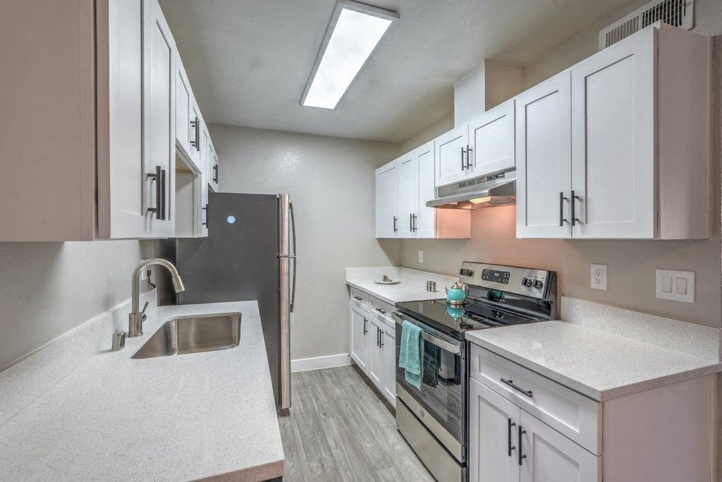 A kitchen with white cabinets and a stainless steel refrigerator.