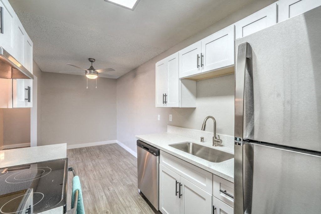 A kitchen with a stove top oven, sink, and refrigerator.