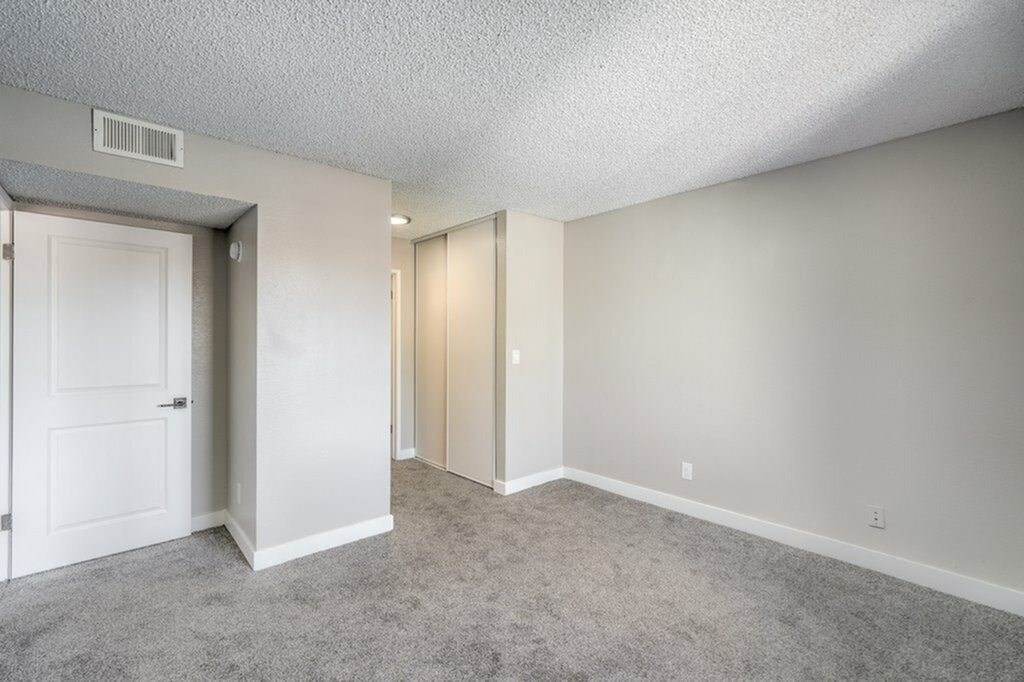 A room with a carpeted floor and two doors.