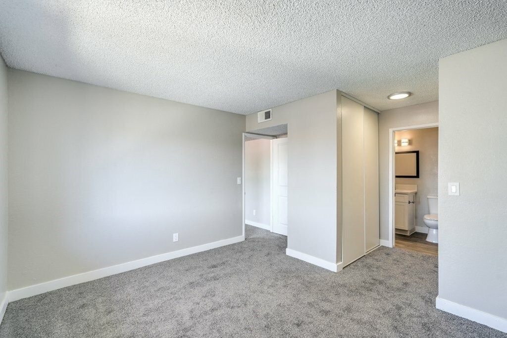 A spacious room with a carpeted floor and a bathroom visible in the background.