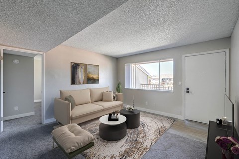 A living room with a beige couch, a coffee table, and a painting on the wall.