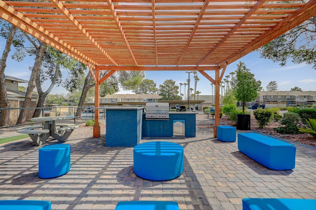 A wooden pergola with blue seating is in the foreground of the image.