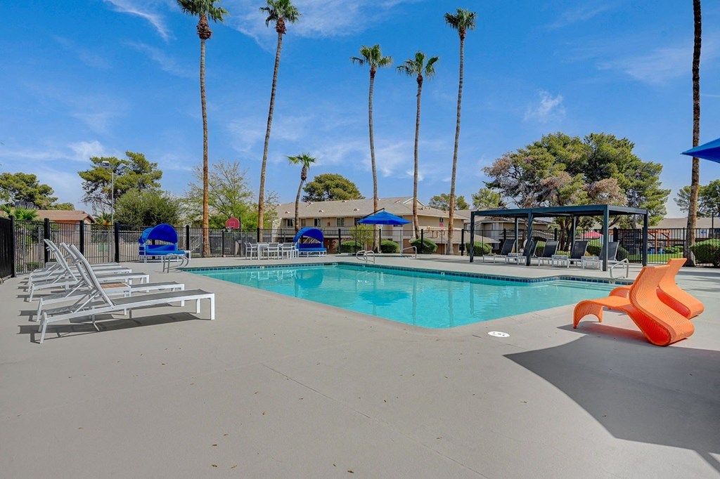 A pool surrounded by palm trees and blue umbrellas.