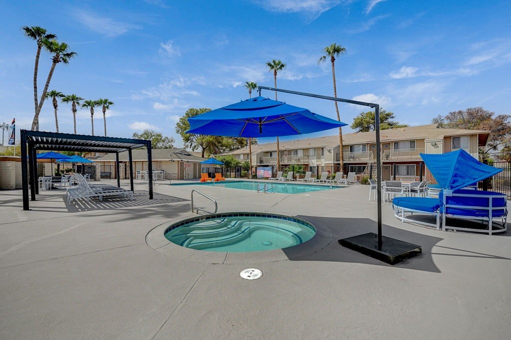 A pool area with a blue umbrella and a hot tub.