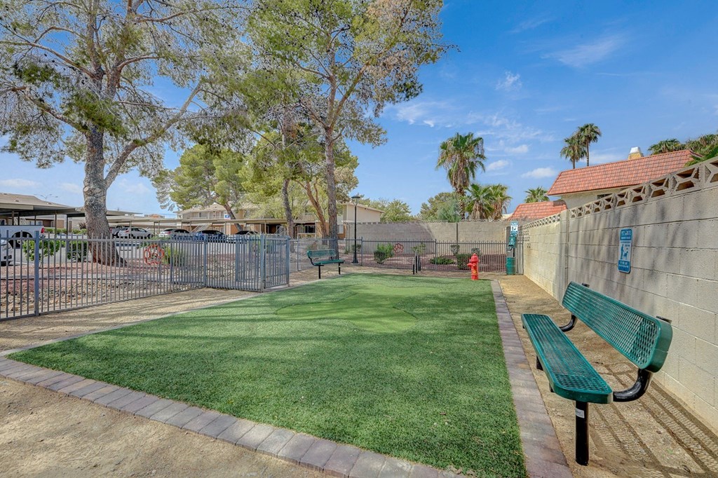 A park with a green bench and a fence.