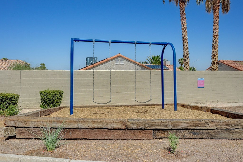A playground swing set with a blue frame and a brown wooden slide.