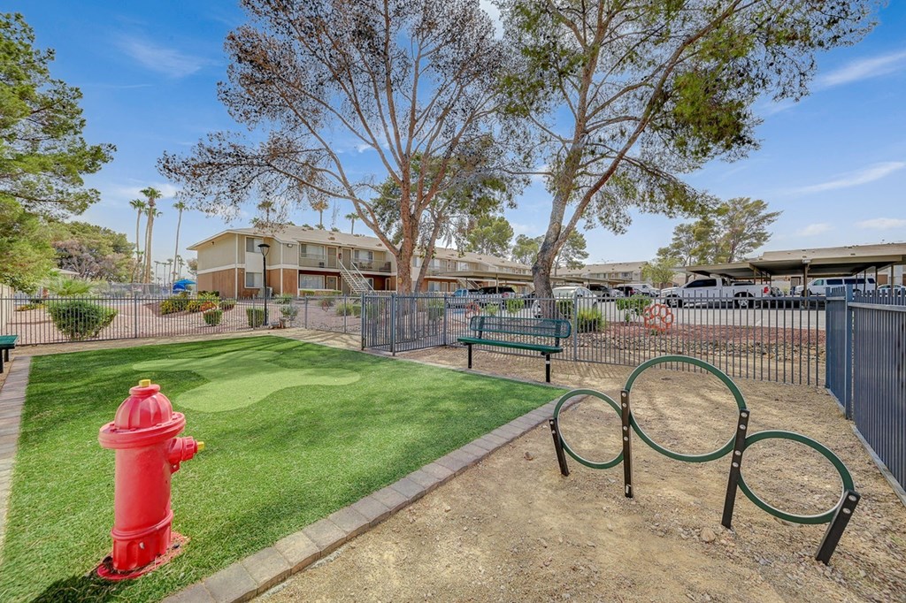A red fire hydrant sits on a green lawn next to a playground.