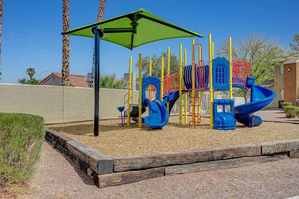 A playground with a blue slide and a green canopy.