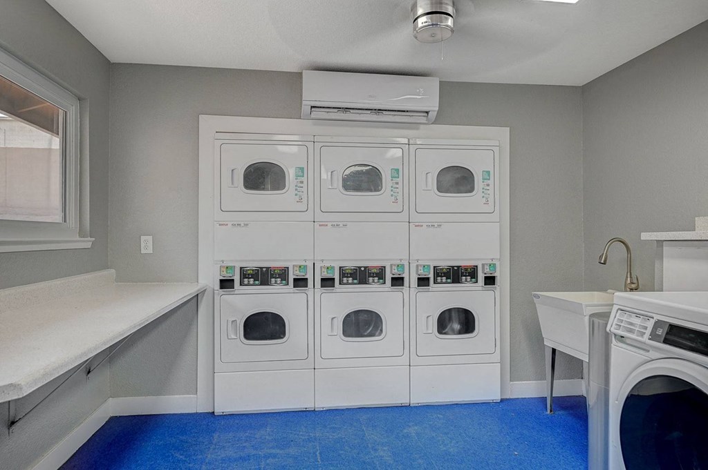 A laundry room with a row of washers and dryers.