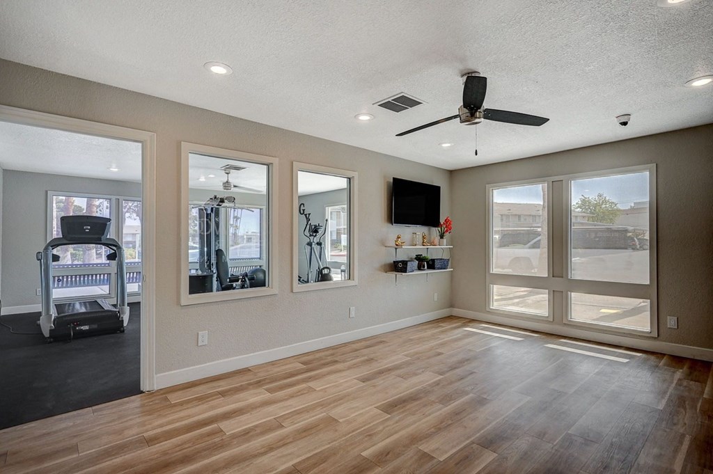 A spacious room with a treadmill and mirrors on the wall.