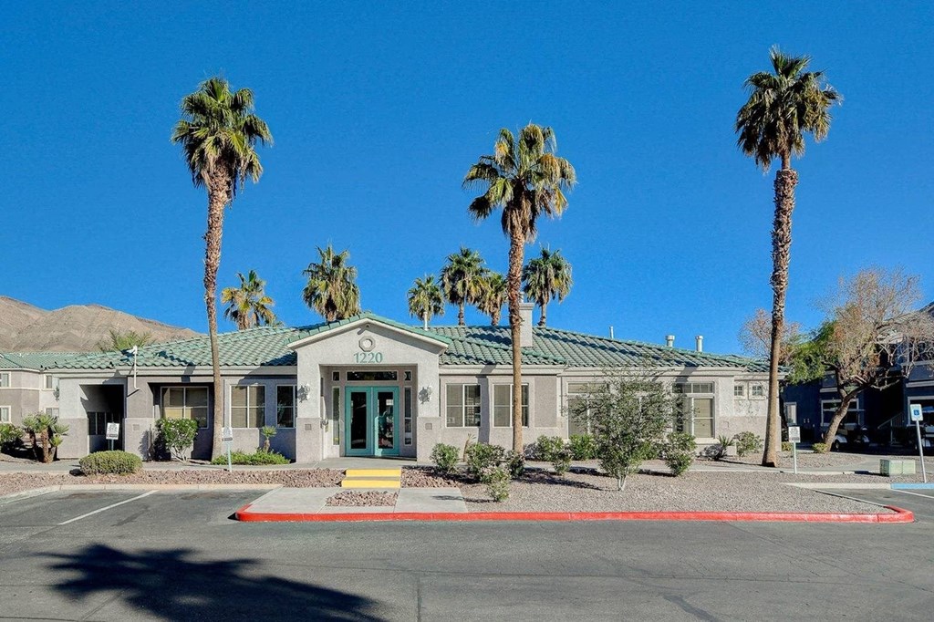 A building with a green door is surrounded by palm trees.