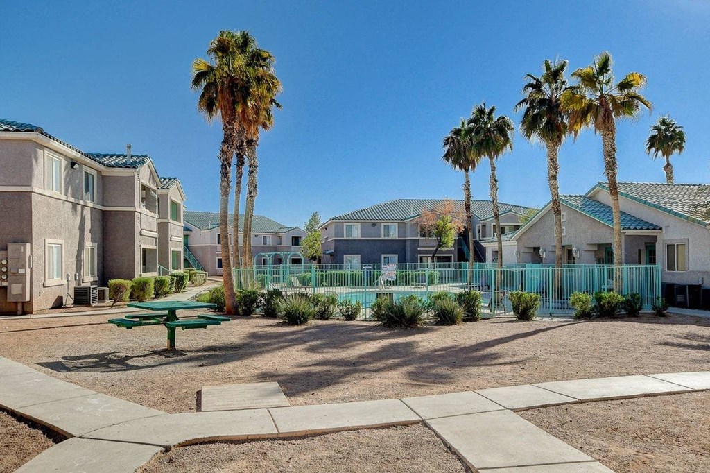 A sunny day at a residential area with palm trees and a green bench.