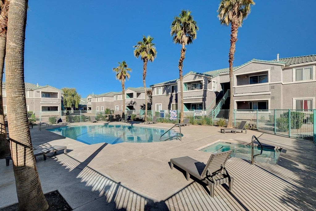 A pool surrounded by palm trees and a bench.