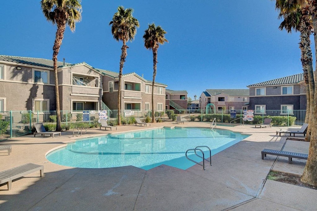 A swimming pool surrounded by palm trees and apartment buildings.