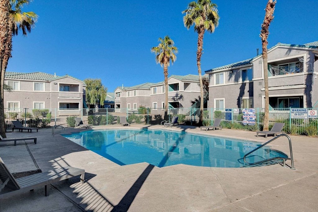 A swimming pool surrounded by palm trees and lounge chairs.