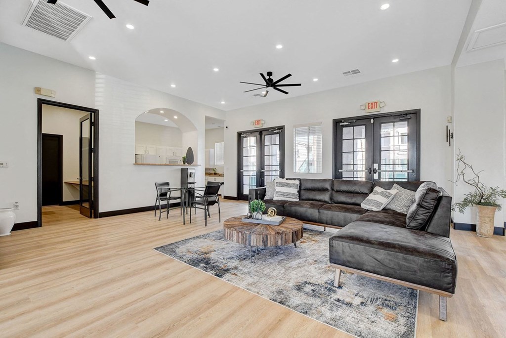 A living room with a black couch and a wooden floor.