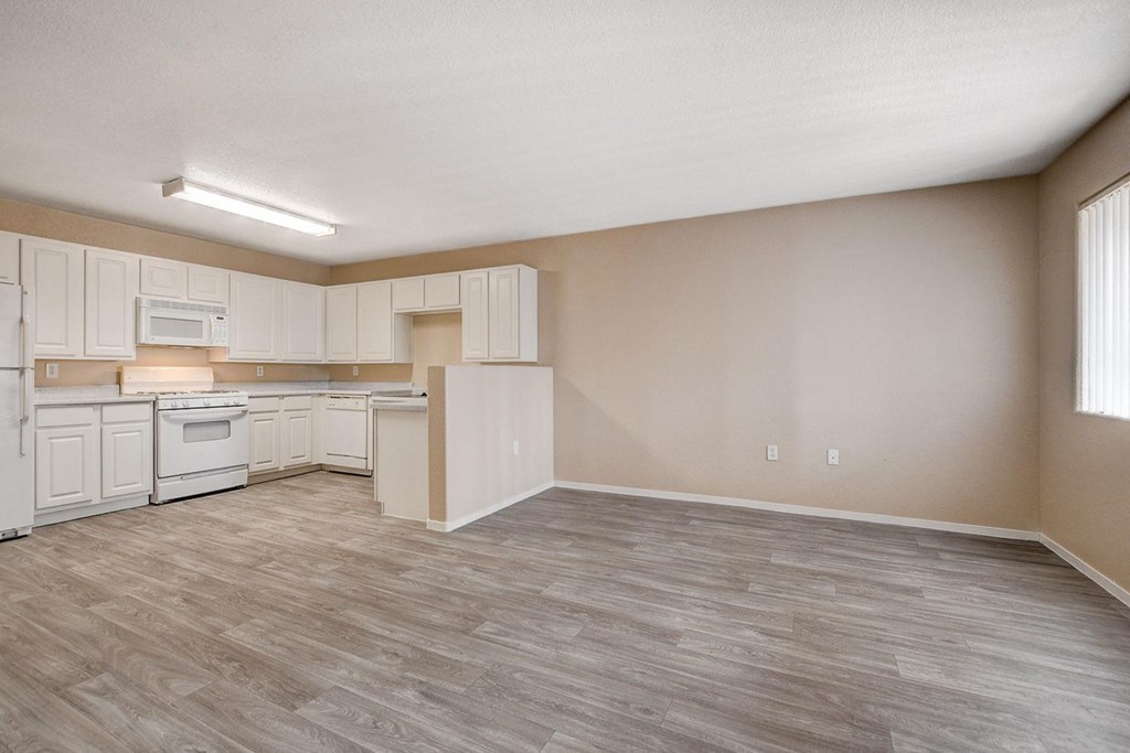 A kitchen with white cabinets and a wooden floor.