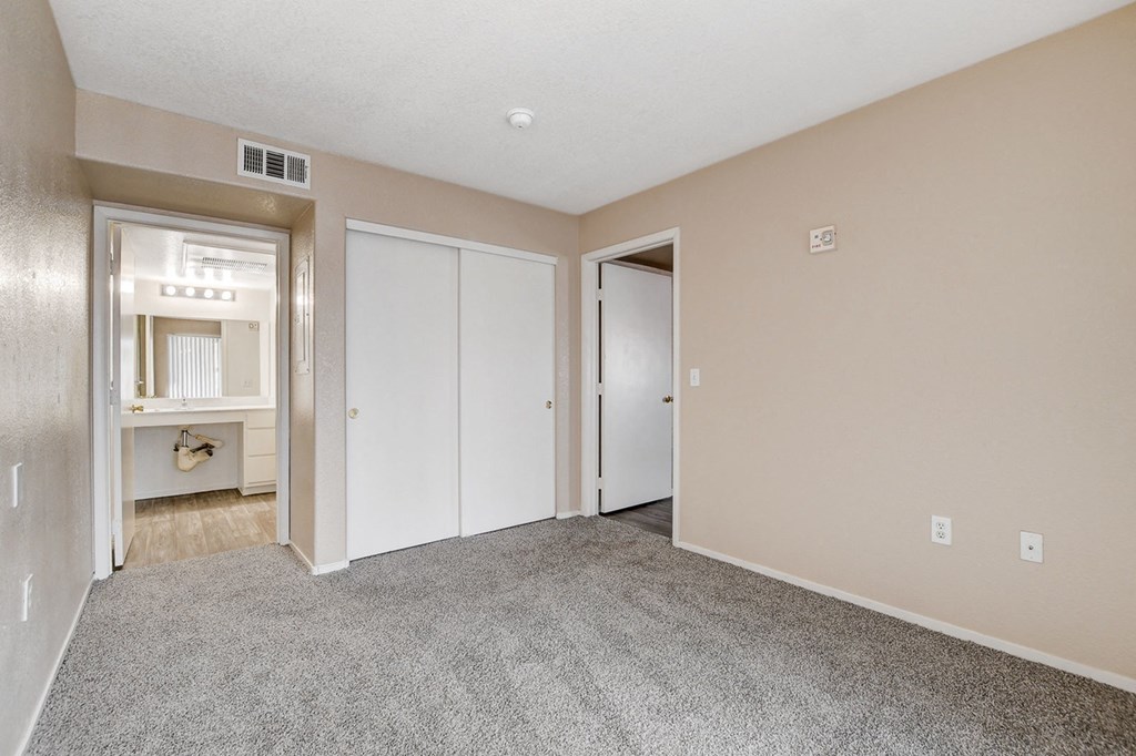 A spacious room with a grey carpet and white doors.