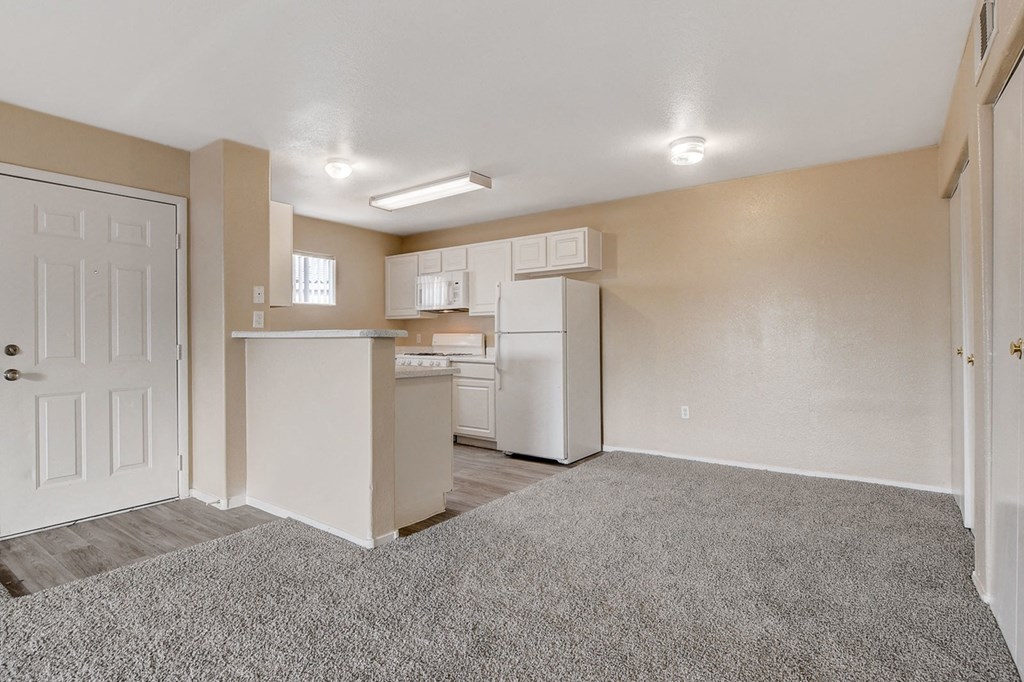 A kitchen area with a white refrigerator and cabinets.