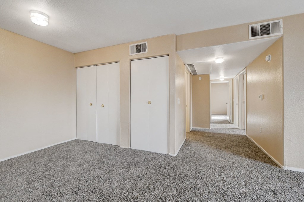 A room with carpeted floor and white walls with three closets.