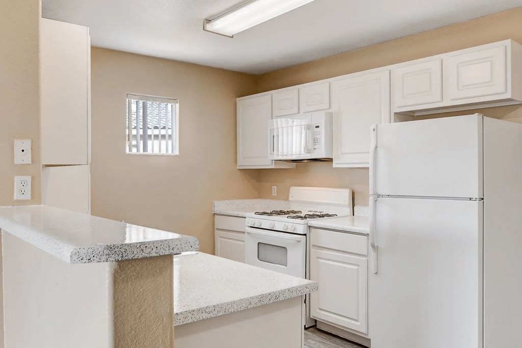 A kitchen with white appliances and a granite counter.