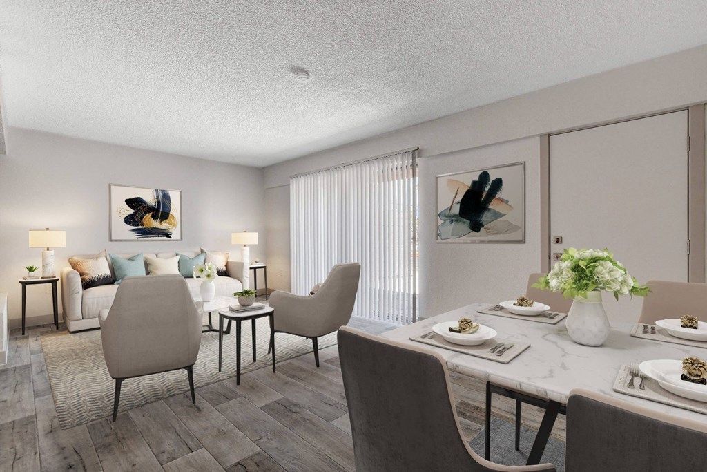 A dining room with a table set for two and a couch with pillows in the background.