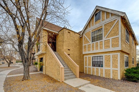 A house with a brown and tan exterior and a staircase leading to the front door.