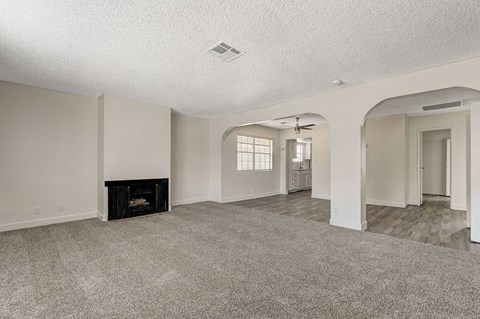 A spacious living room with a fireplace and a ceiling fan.