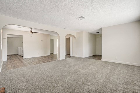 A spacious room with a carpeted floor and white walls.