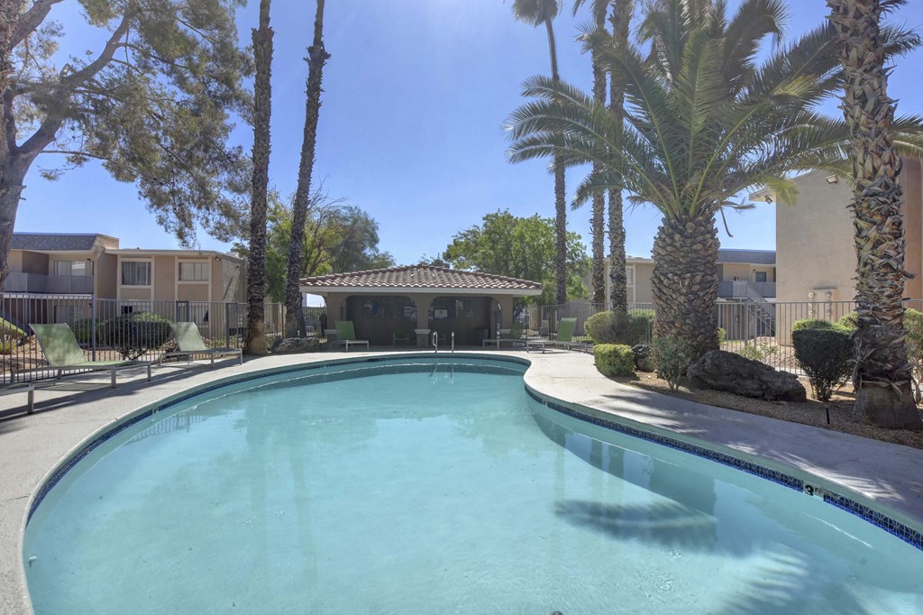 A swimming pool surrounded by palm trees and a building in the background.