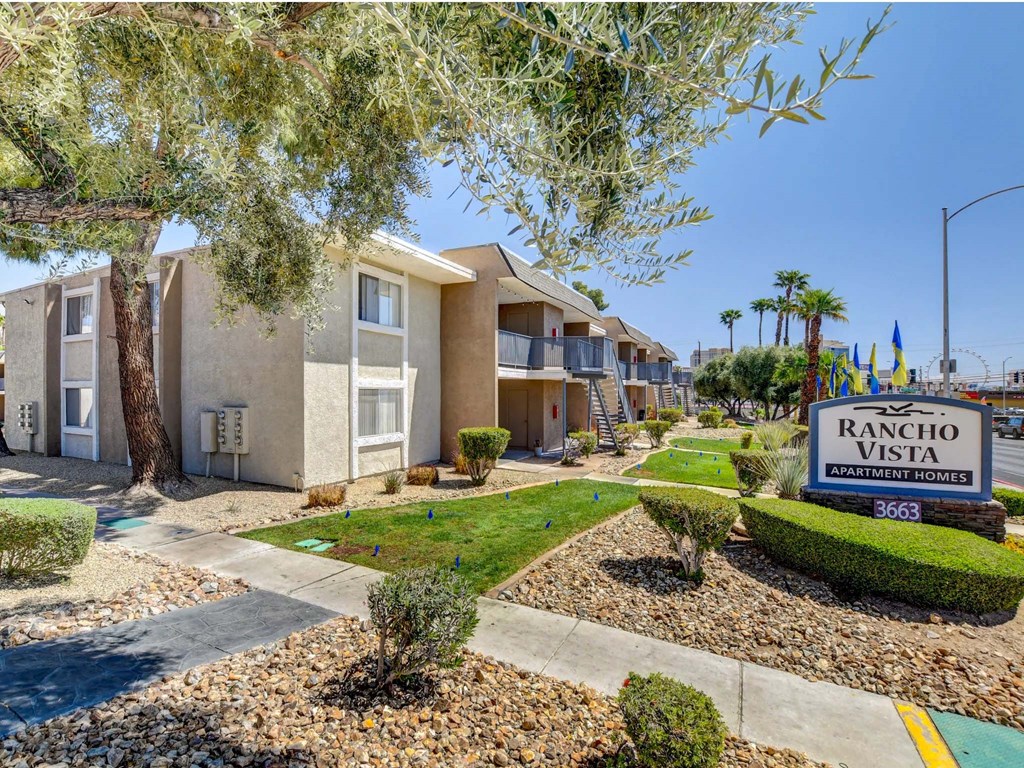 A Rancho Vista Apartments sign is in front of a building with a landscaped yard.