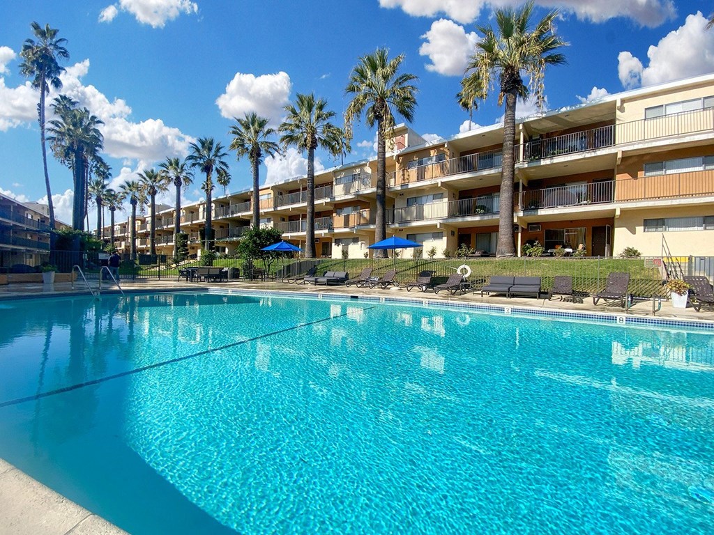 A large swimming pool in front of a building with palm trees.