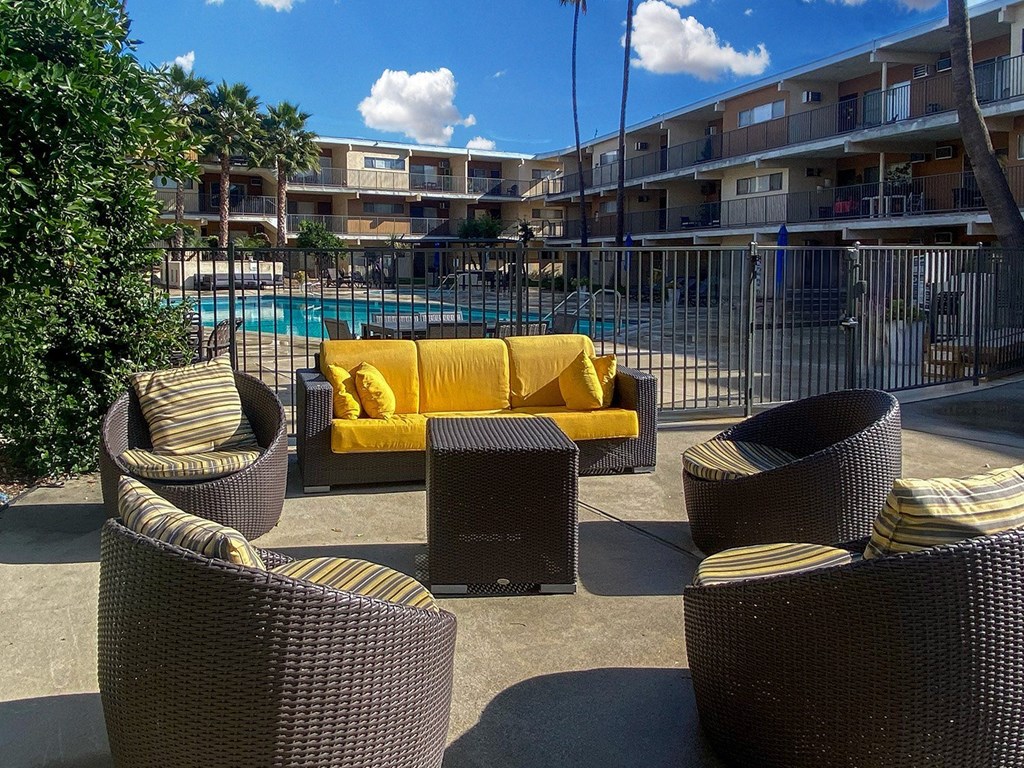 A poolside area with wicker furniture and a yellow cushion.