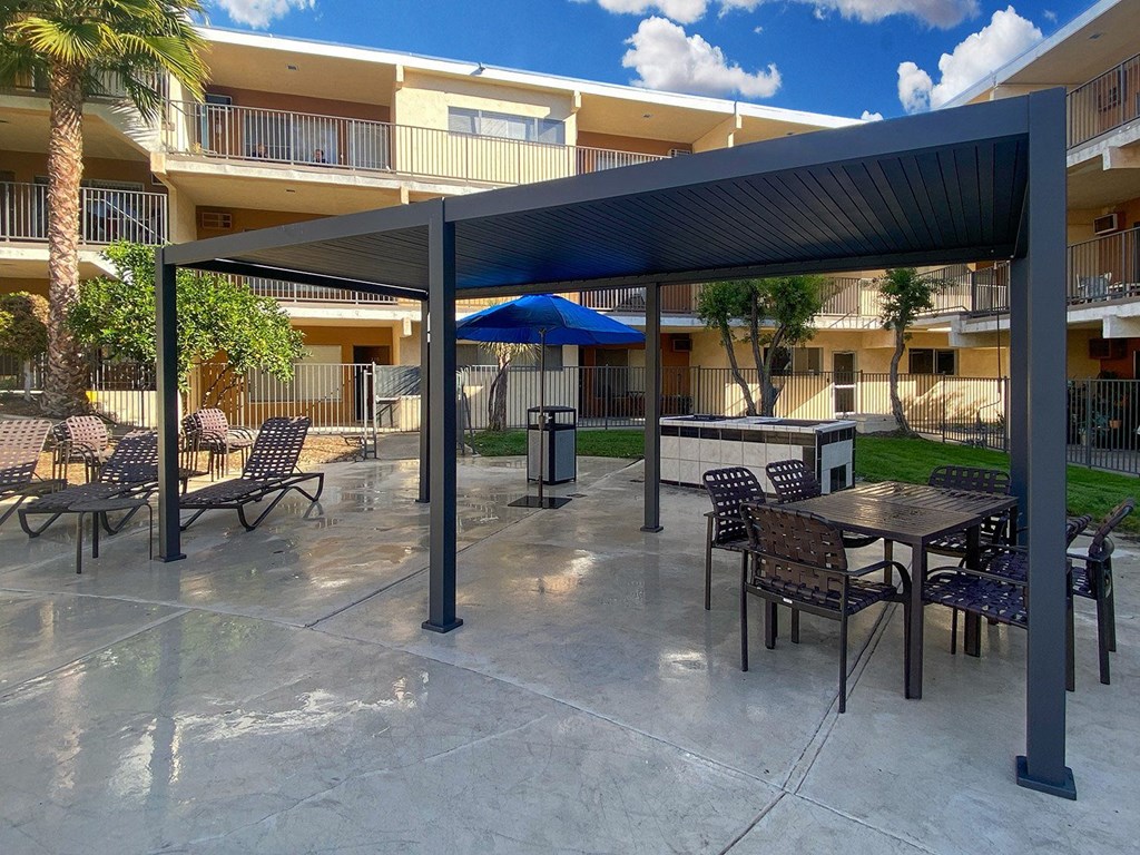 A patio area with tables and chairs under a canopy.