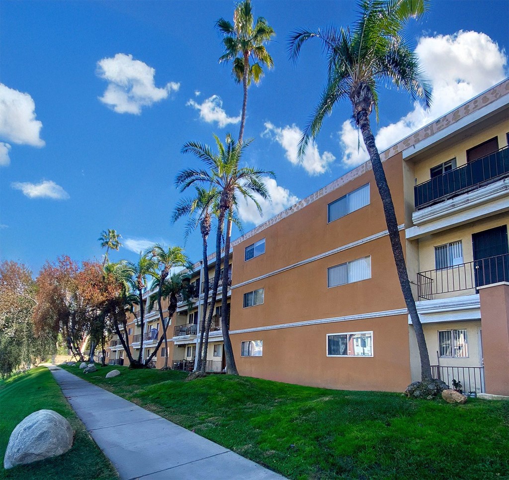A building with a balcony and a palm tree in front of it.