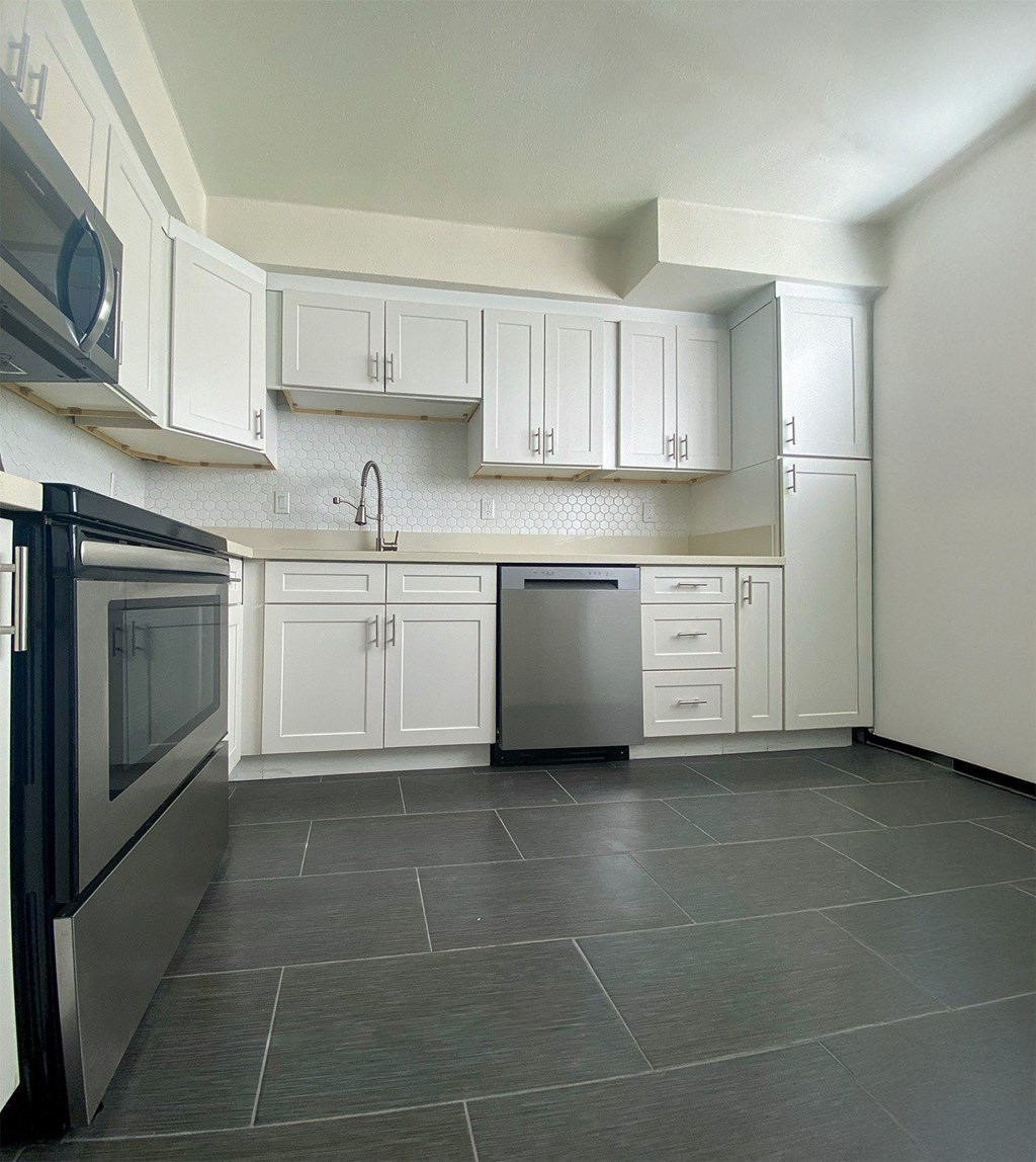 A kitchen with white cabinets and a black fridge.