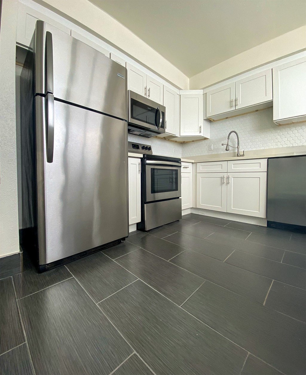A modern kitchen with a stainless steel refrigerator and microwave.