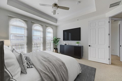 A bedroom with a bed, a television, and a ceiling fan.