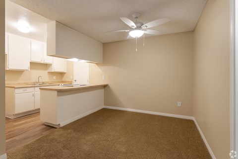 A kitchen with white cabinets and a fan on the ceiling.