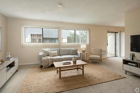 A living room with a grey couch, a coffee table, and a flat screen TV.
