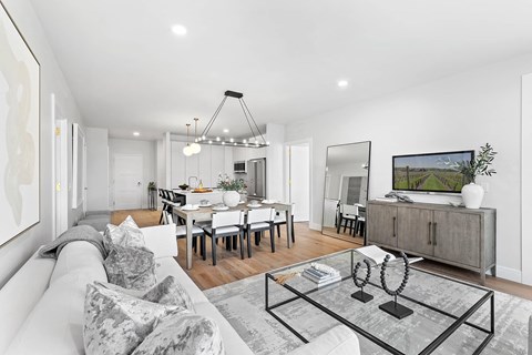A modern living room with a grey sofa and a glass coffee table.