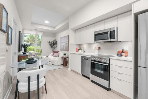 A modern kitchen with white cabinets and a glass table.
