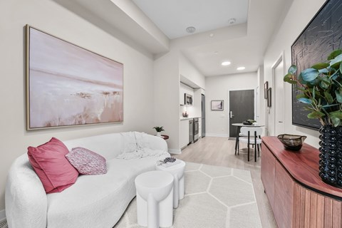 A living room with a white couch and a painting on the wall.