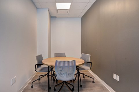A conference room with a round table and four chairs.