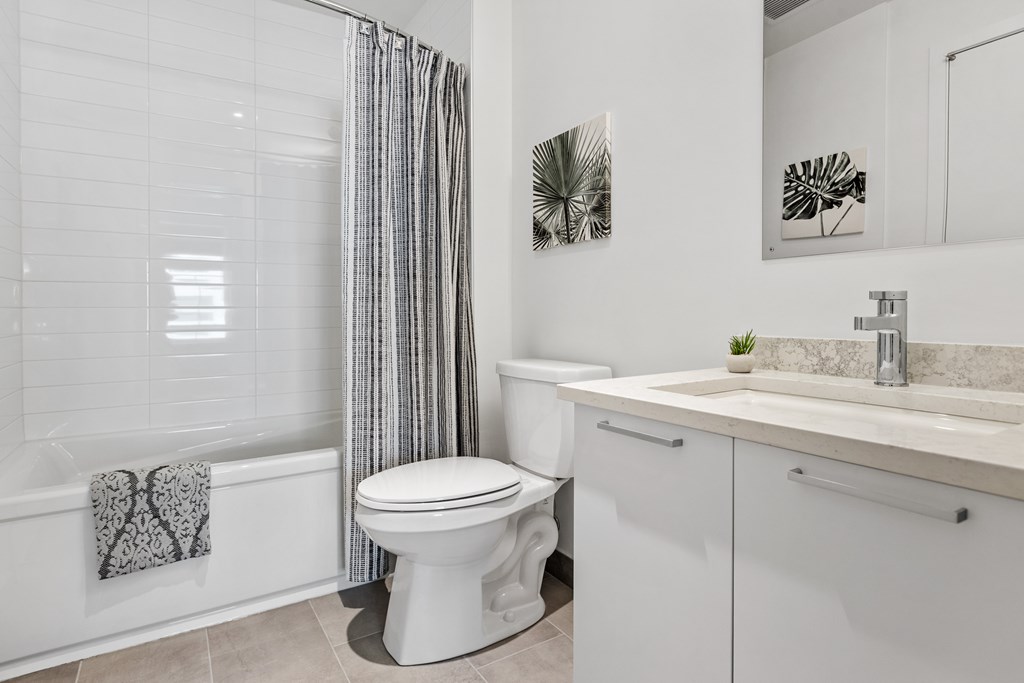A white bathroom with a toilet, sink, and shower.