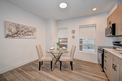 A dining room with a table set for two and a painting on the wall.